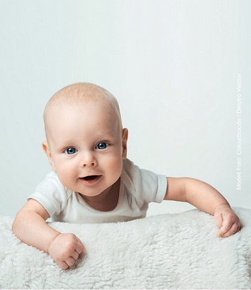 Ein lächelndes Baby liegt auf einer Decke
